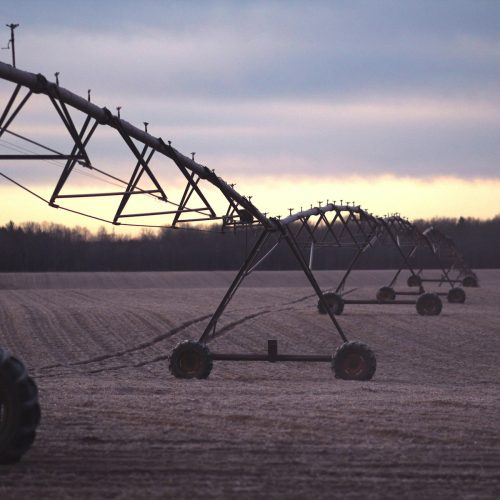 photo of black farming equipment under white clouds at daytime
